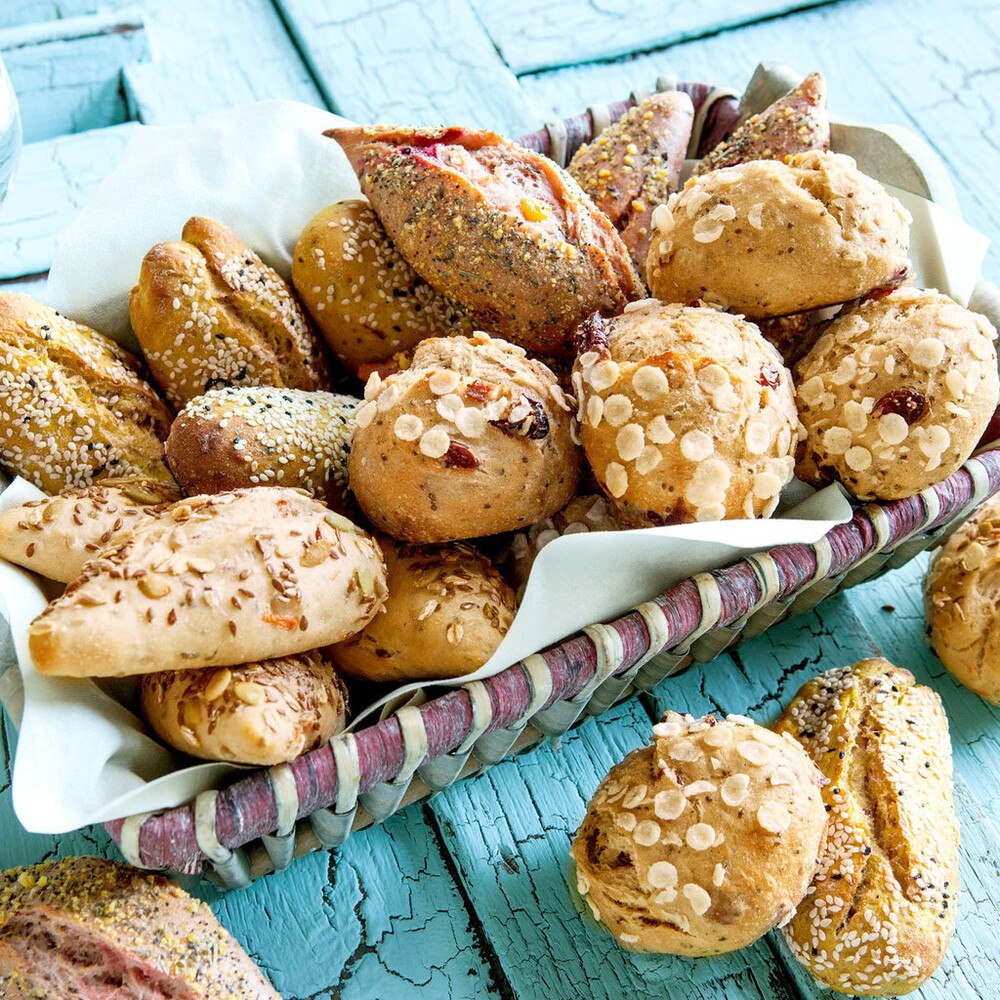 Mischkiste mit je 20 Midi-Weckerln in den vier Sorten: Dinkelweckerl Chia, Cranberry und Reisflakes / Weizenweckerl Karotte und Saatendekor / Weizenweckerl Rote Bete, Mais und Maisgrieß-Dekor sowie Weizenweckerl Curry, Kichererbsen und getrocknete Tomaten. © Edna Backwaren